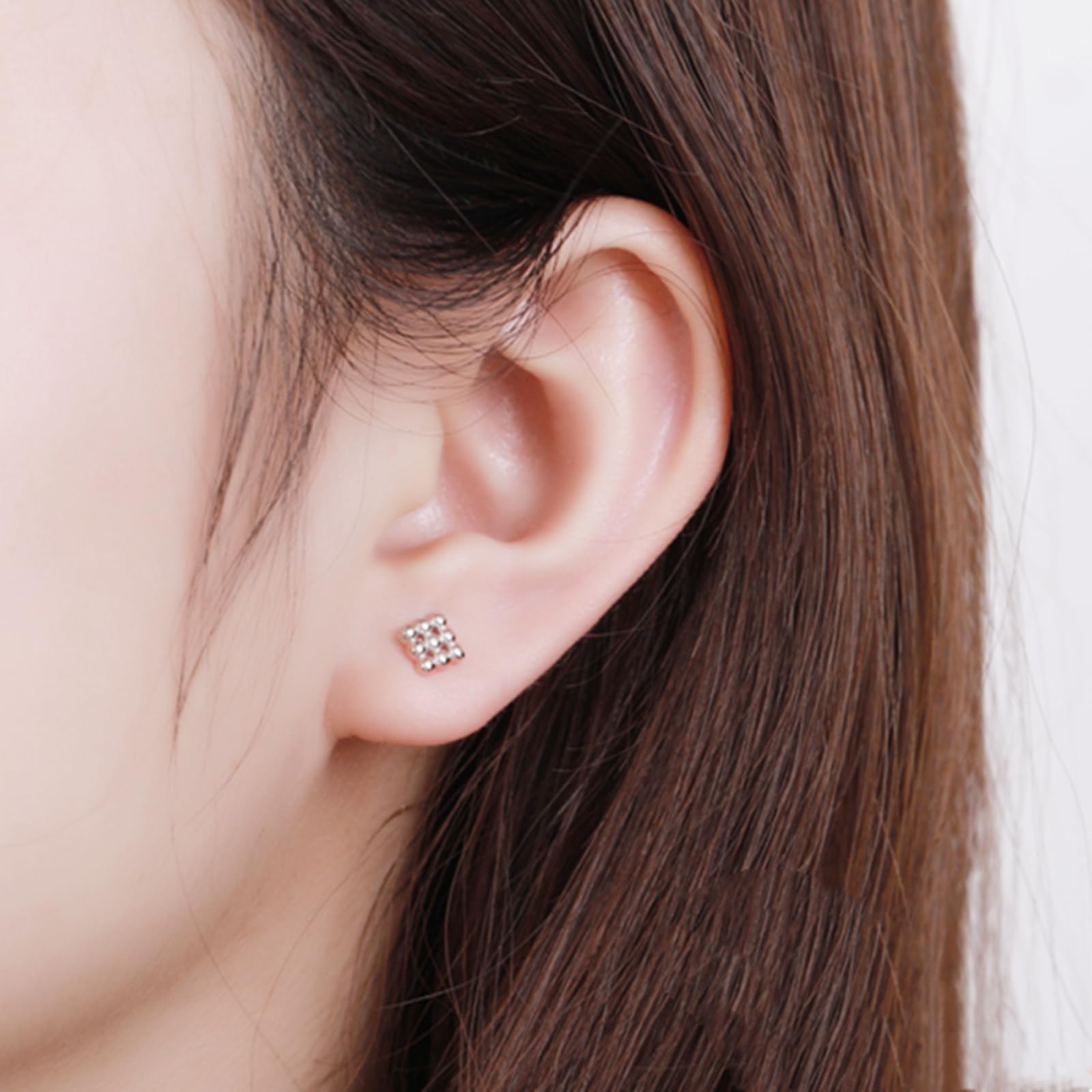 Mini geometric stud earrings on ear: cube design with small bead cluster