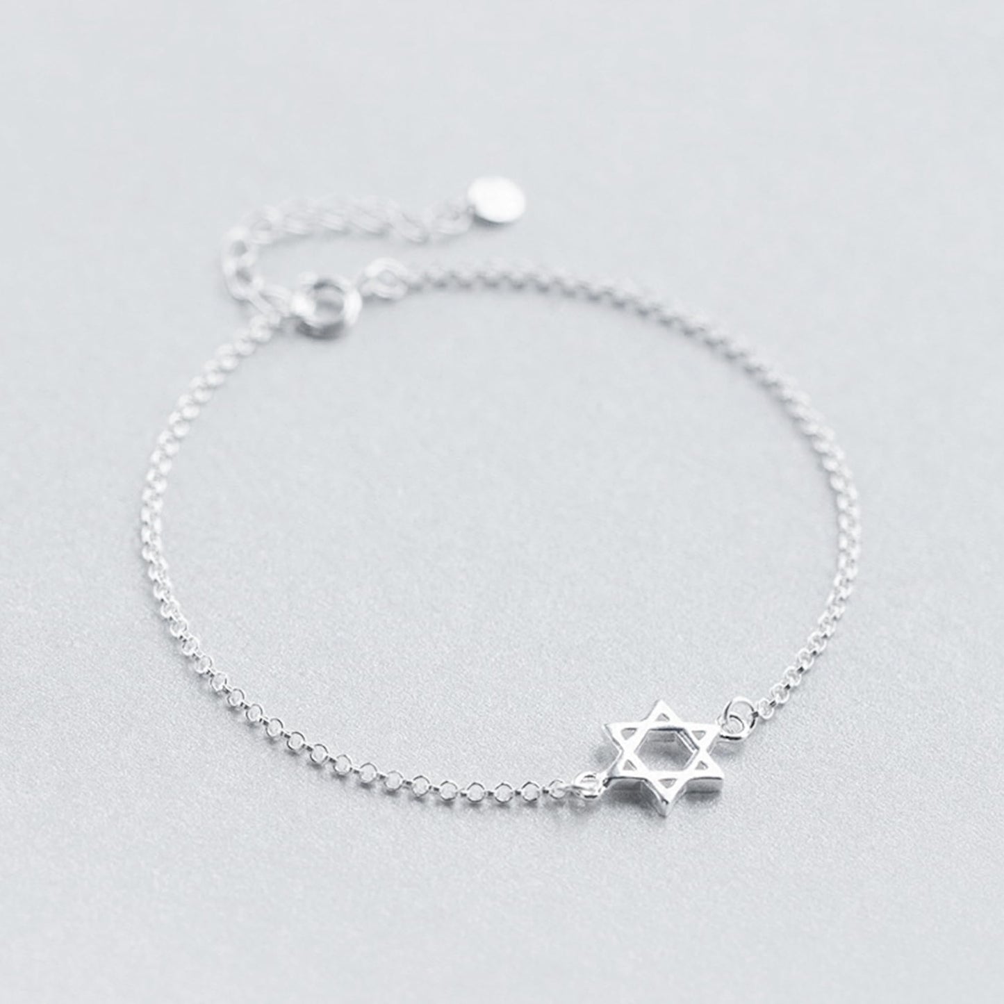 Silver Star of David bracelet with star charm and round clasp at top.