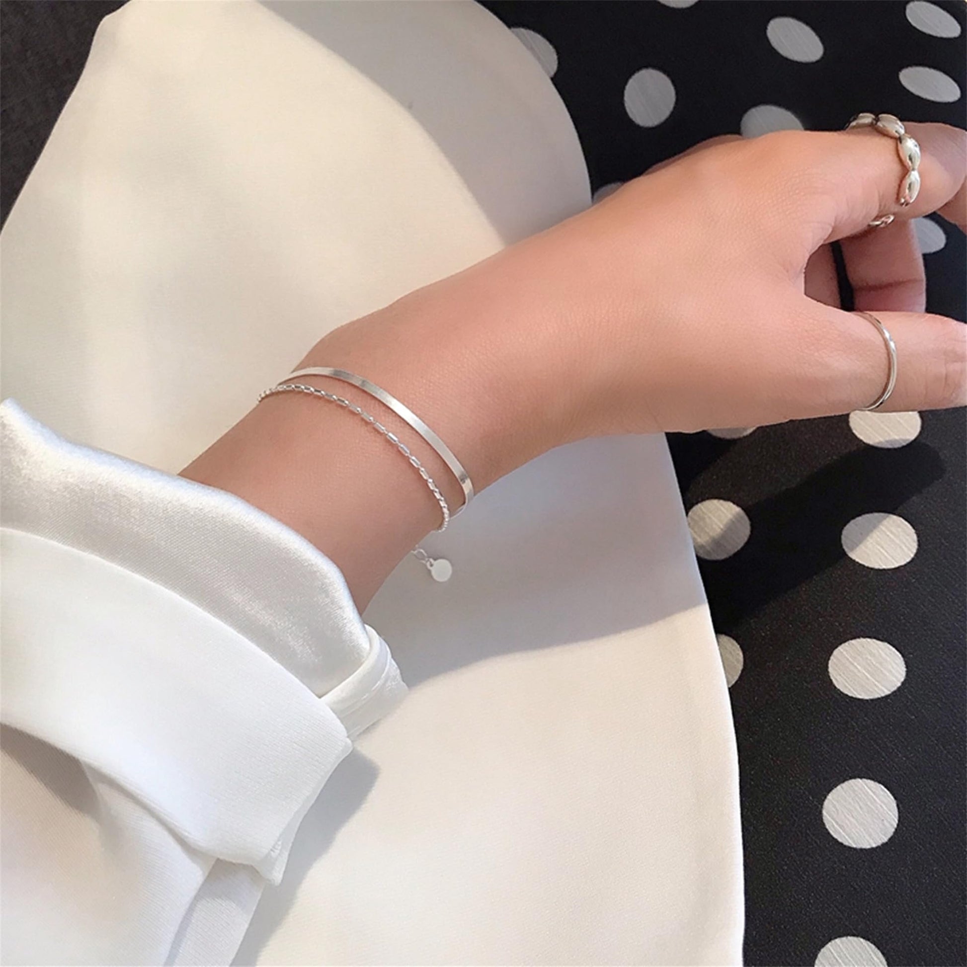 Layered snake bead bracelet on wrist with round pendant and snake chain links
