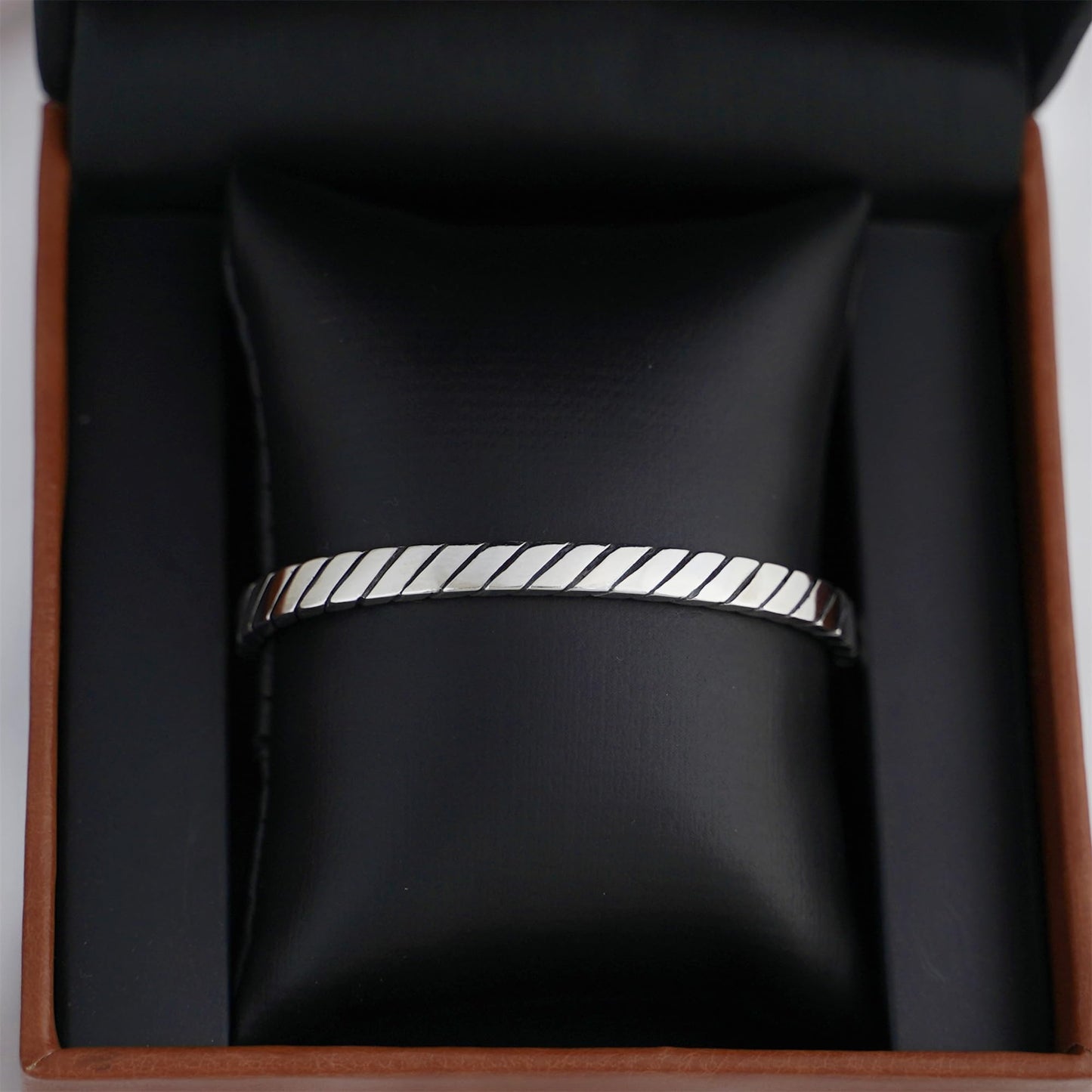 Oxidised rope cuff bangle on display, continuous ridged rope pattern