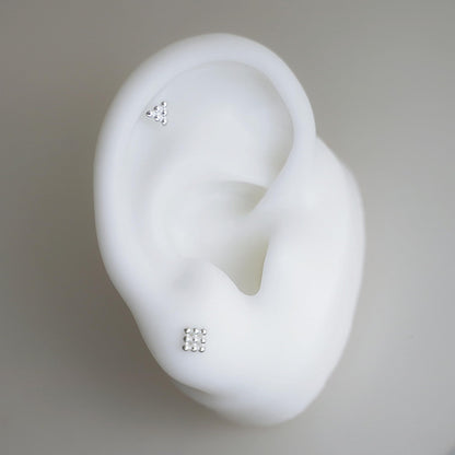 Mini geometric studs on ear-shaped holder: cube and triangle studs
