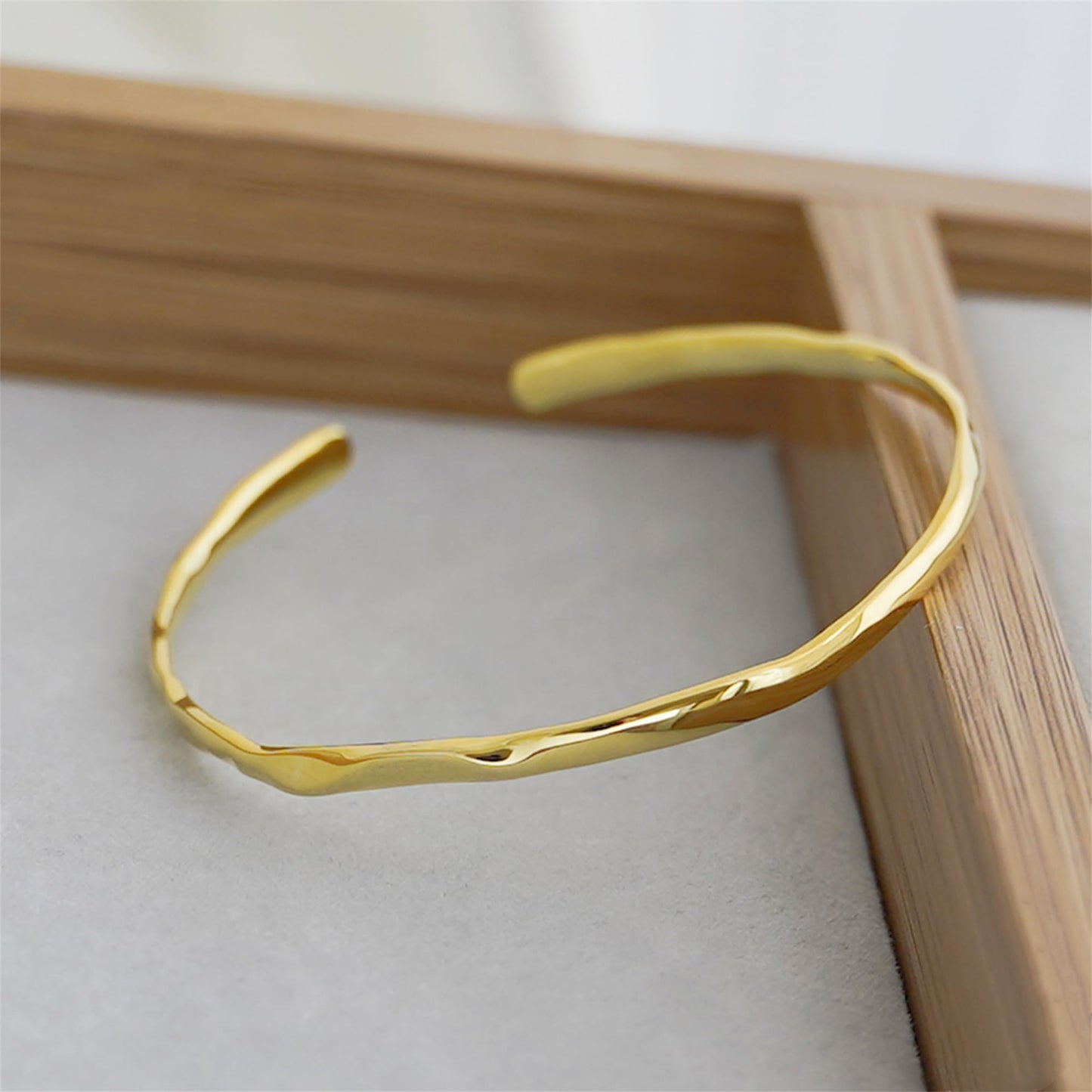 Hammered 18K gold cuff bracelet with curved band on display
