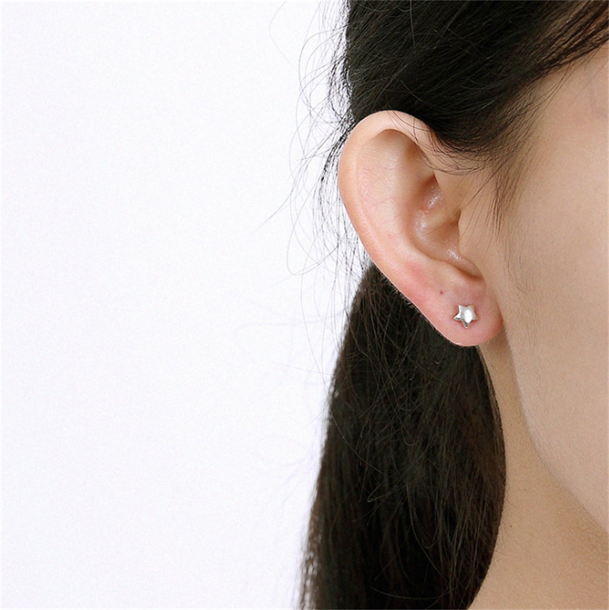 Puffy Star Studs am Ohr: kleine silberfarbene Stern-Ohrstecker
