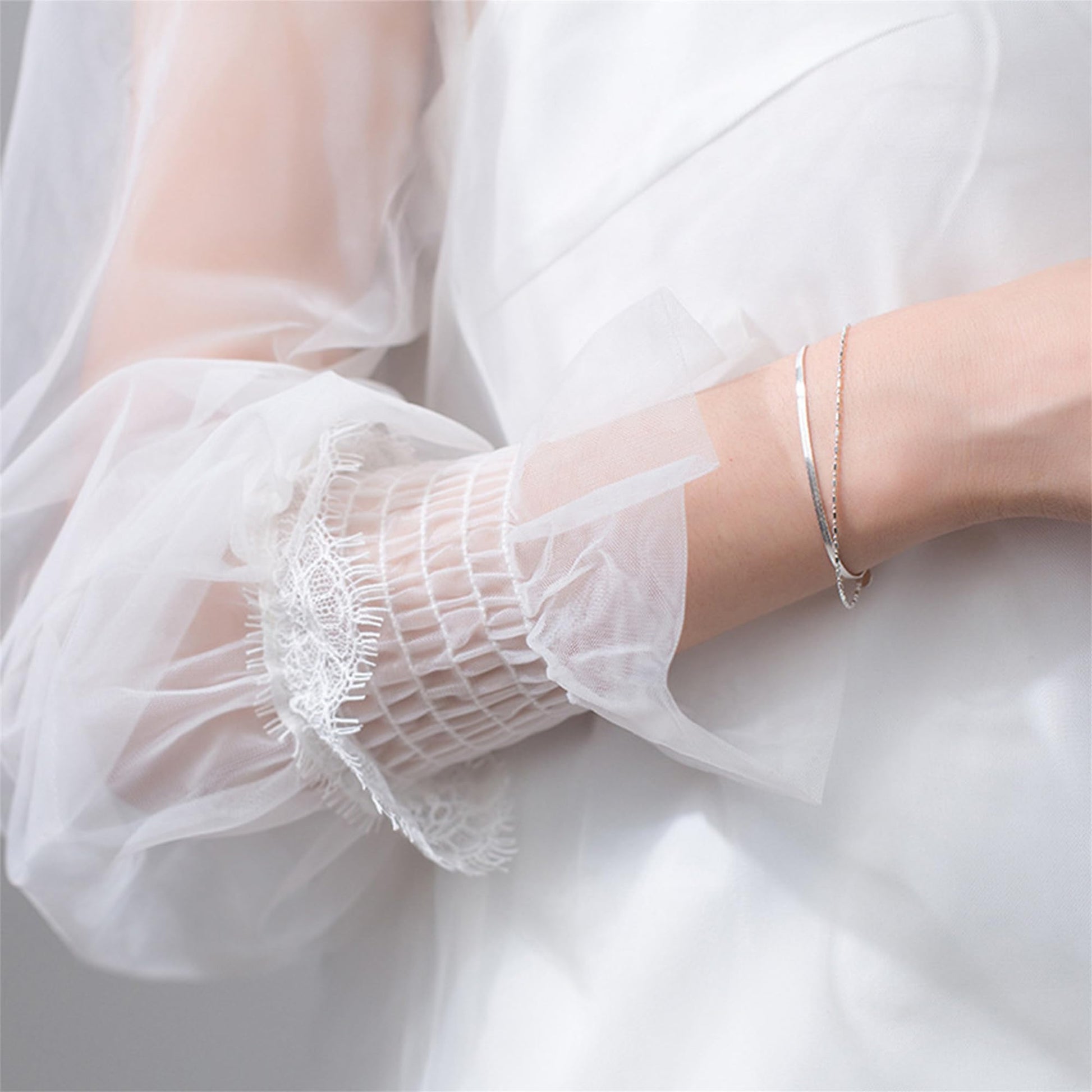 Layered snake bead bracelet on ankle-length dress sleeve with slim chain layers