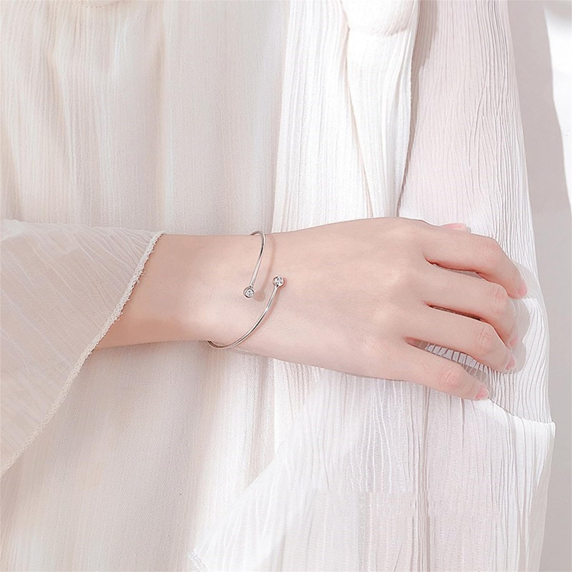 CZ torque bangle worn on wrist, silver tone with two round clear stones