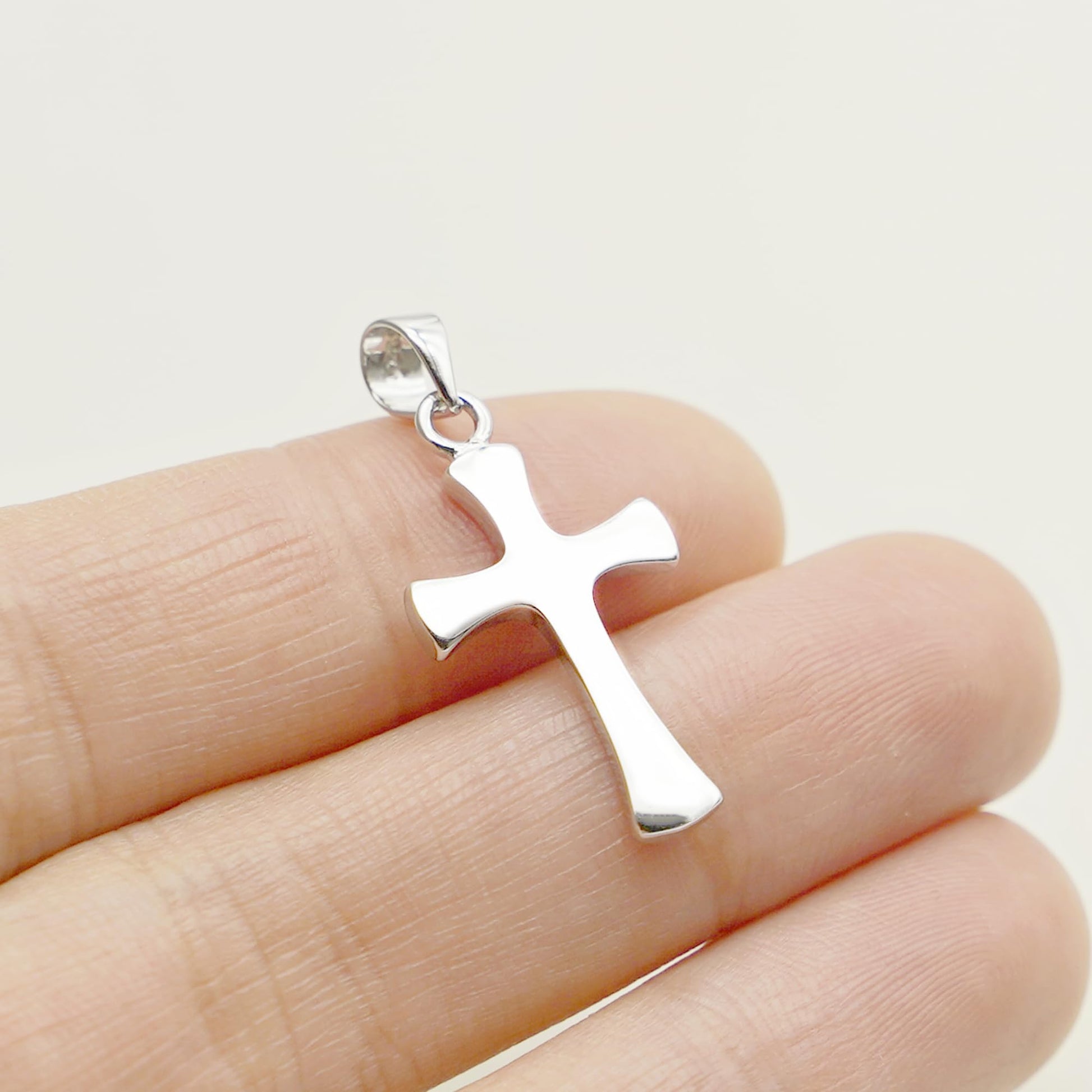 Close-up of silver-tone flared cross pendant with looped bail