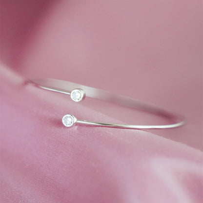 Bezel-set CZ torque bangle detail: two round stones on silver bar