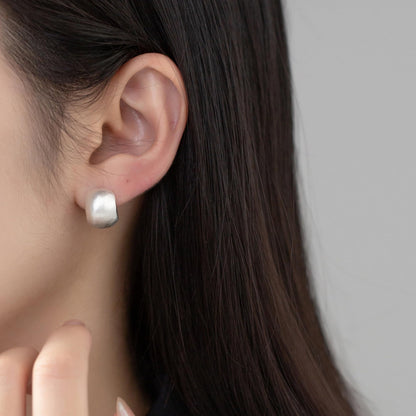 Brushed half-hoop drop earrings worn on ear, silver domed half-hoop