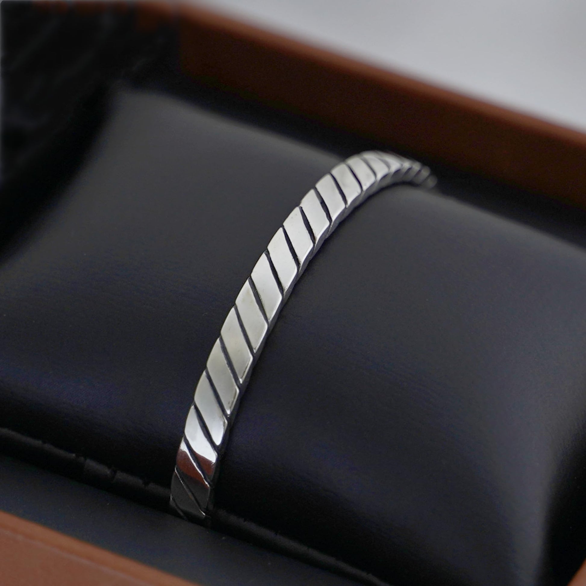 Oxidised rope cuff bangle angled view, ribbed silver bars with oxidised seams
