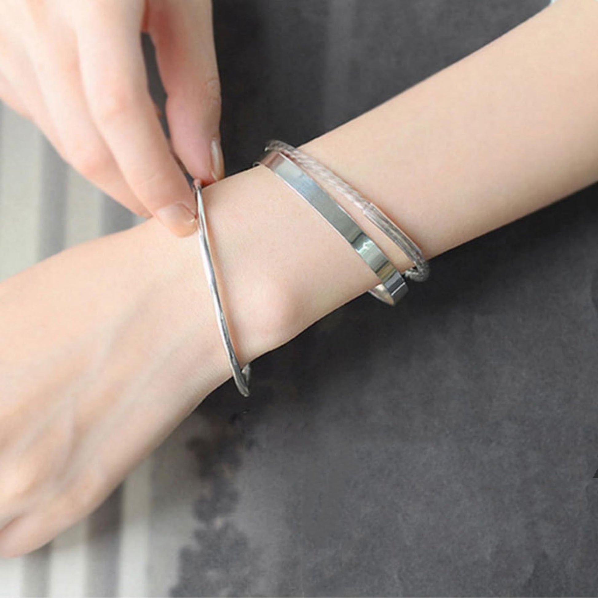 Polished cuff bangle on wrist, shiny silver band with adjustable open end