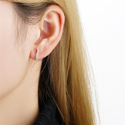 Wavy vine climber stud earrings worn, visible curved wave shape at the ear