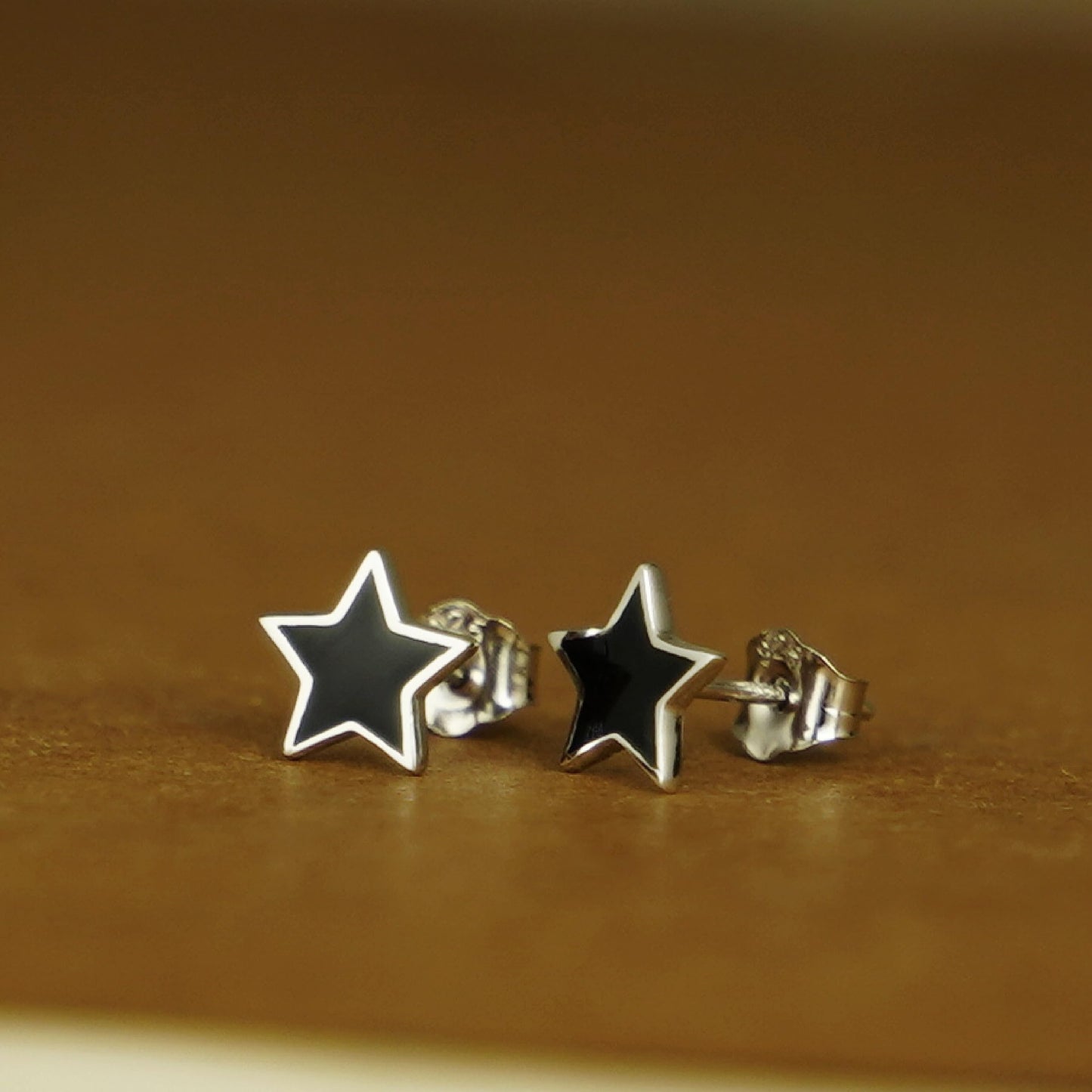 Black star stud earrings with silver-tone hinged post backing