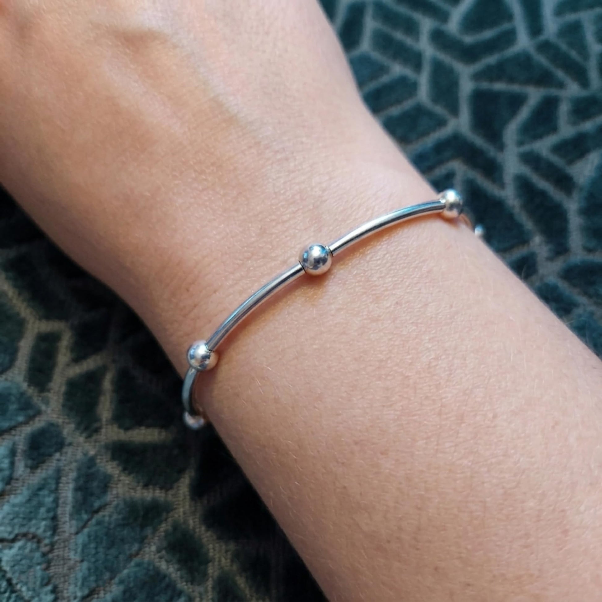 Silver stretch bracelet with three round bead segments on a wrist