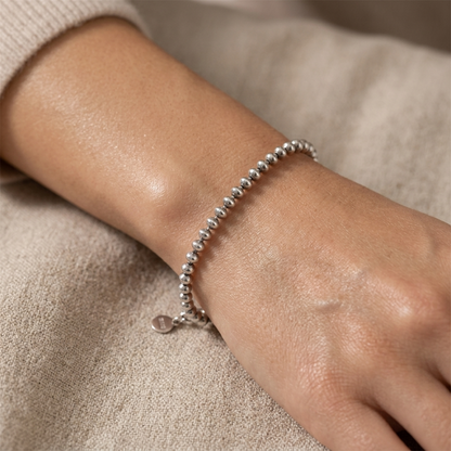 Oxidised flat bead bracelet on wrist, silver-toned round beaded chain