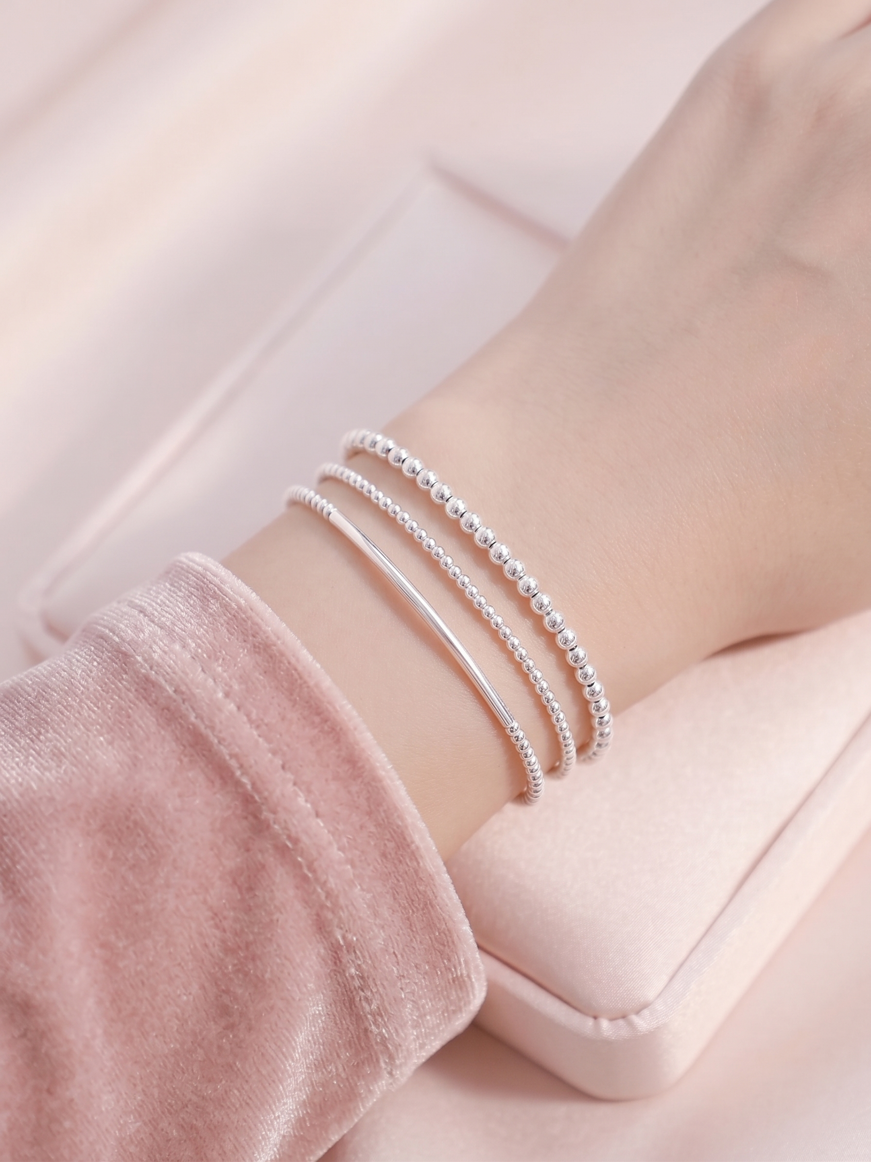 Stacked silver stretch bracelets with beaded strands and curved metal bars