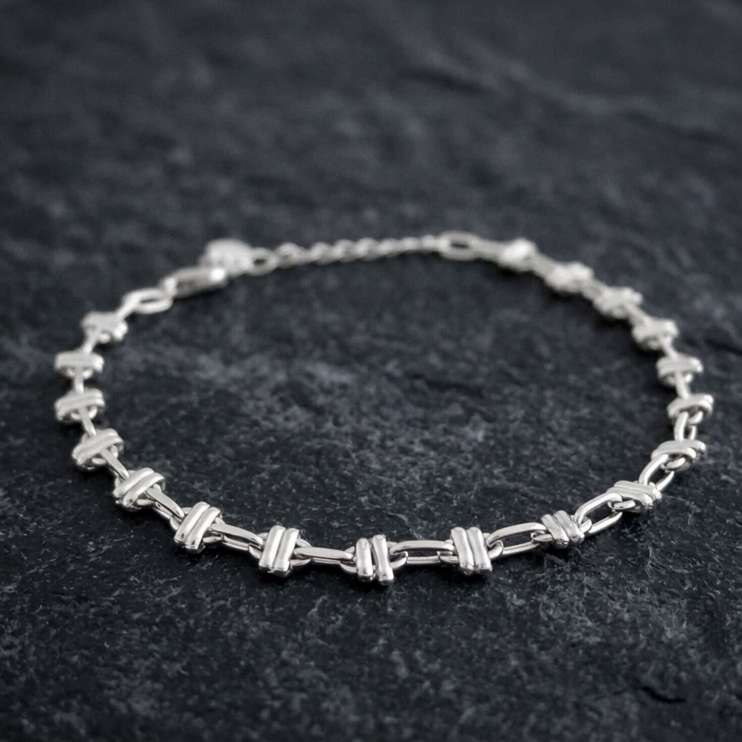 Close-up oval rope curb bracelet: oval link bars on silver-tone curb chain