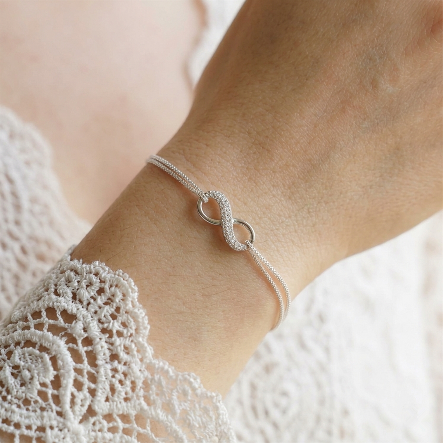 CZ infinity bracelet on wrist; silver-tone chain with linked infinity charm