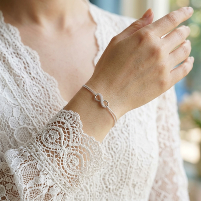 CZ infinity bracelet worn with lace top; silver-tone chain and infinity charm