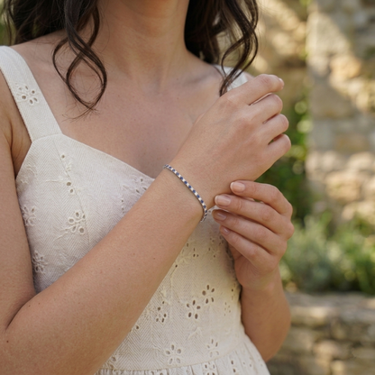 Sapphire tennis bracelet on wrist, blue gemstone row in a slim silver-toned band