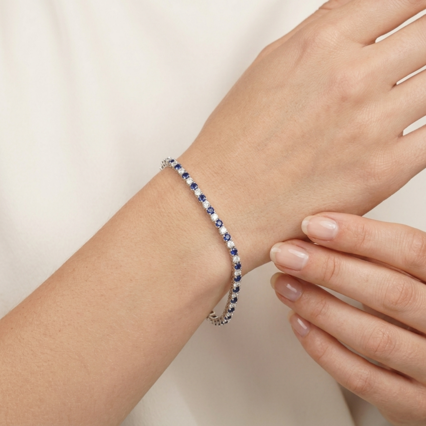 Sapphire tennis bracelet worn on wrist, blue stones with clear sparkling edges