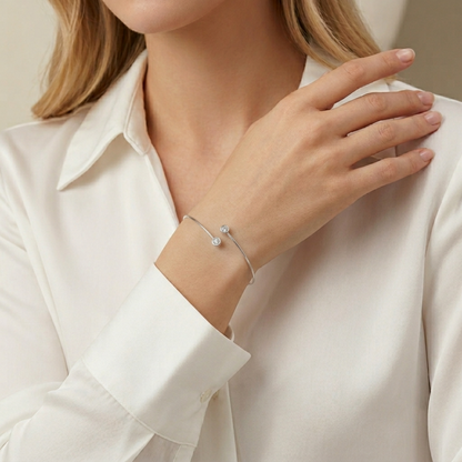 Silver-tone torque bangle on wrist with two round CZ stones, worn with white sleeve