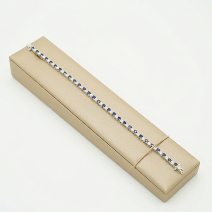 Sapphire tennis bracelet laid on a box: blue gemstone row with clear accents