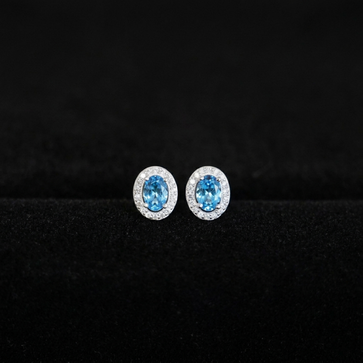 Blue oval CZ halo stud earrings with clear pavé border, silver-tone