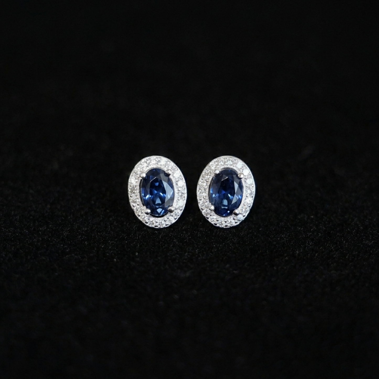 Deep navy oval CZ halo stud earrings with clear pavé halo, silver-tone