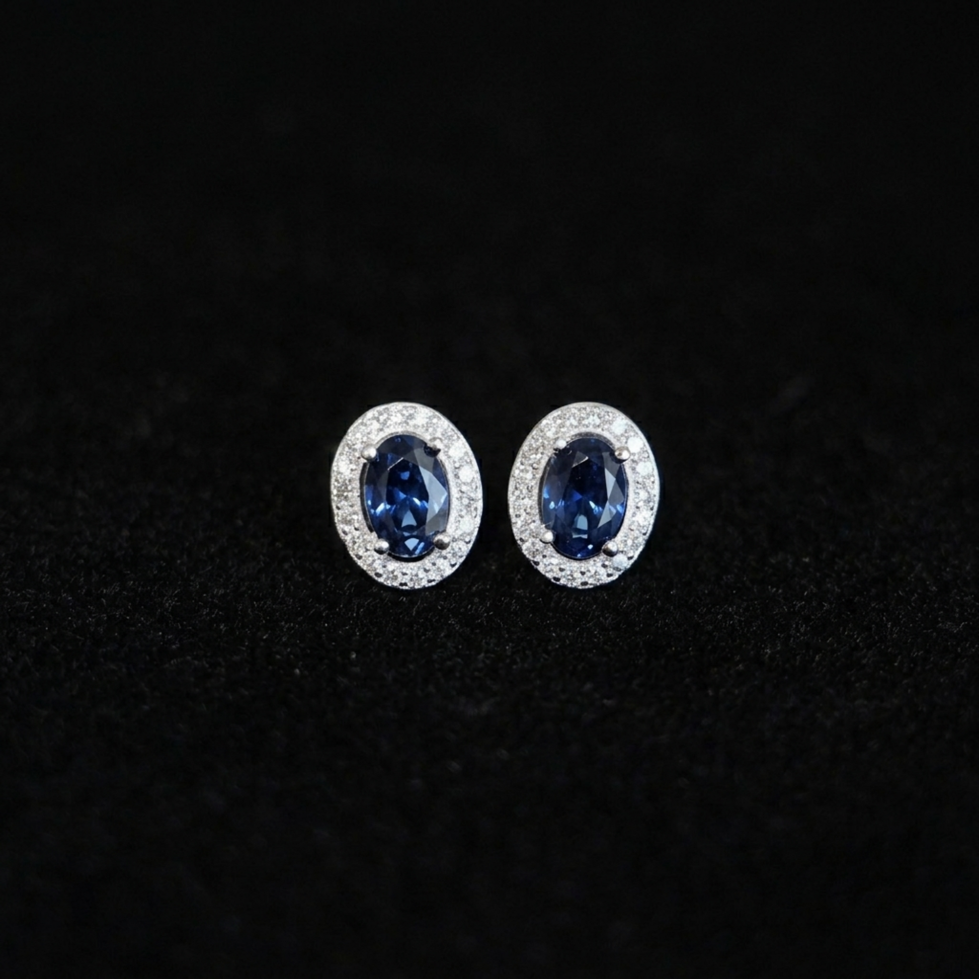 Deep navy oval CZ halo stud earrings with clear pavé halo, silver-tone