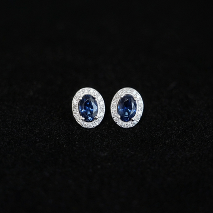 Deep navy oval CZ halo stud earrings with clear pavé halo, silver-tone