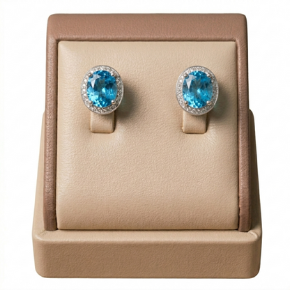 Blue topaz CZ halo studs: oval light-blue center stones with clear halo and prongs.
