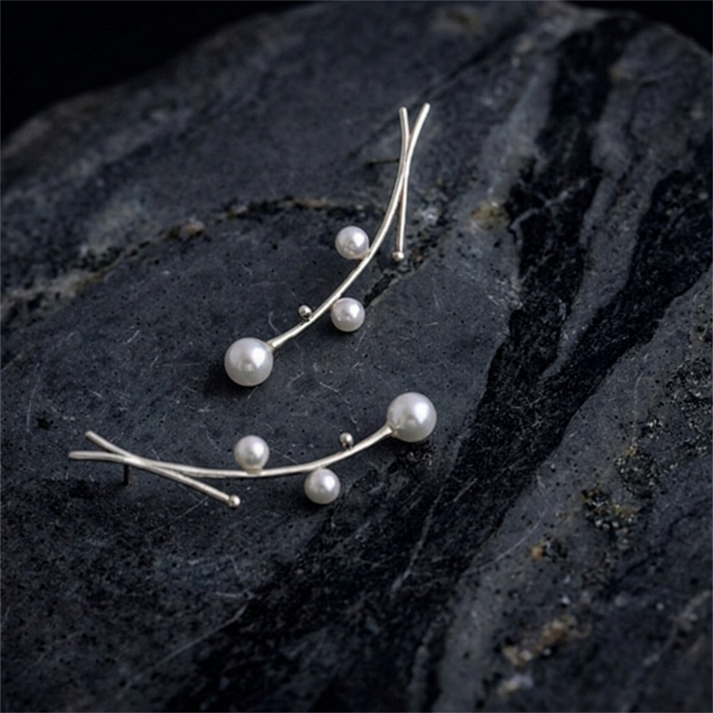 Mistletoe pearl drop earrings on dark surface: two earrings with dangling pearls