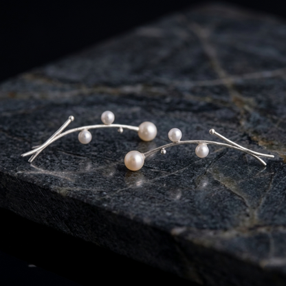 Pair of pearl drop earrings laid flat: thin curved wire with round pearls