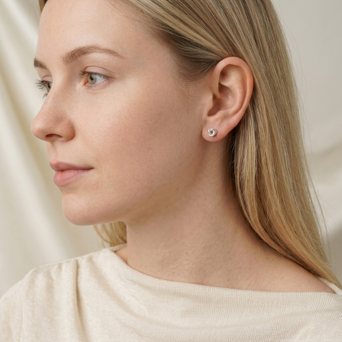 Silvertone Celtic Trinity knot stud earrings on ear, pin backs visible