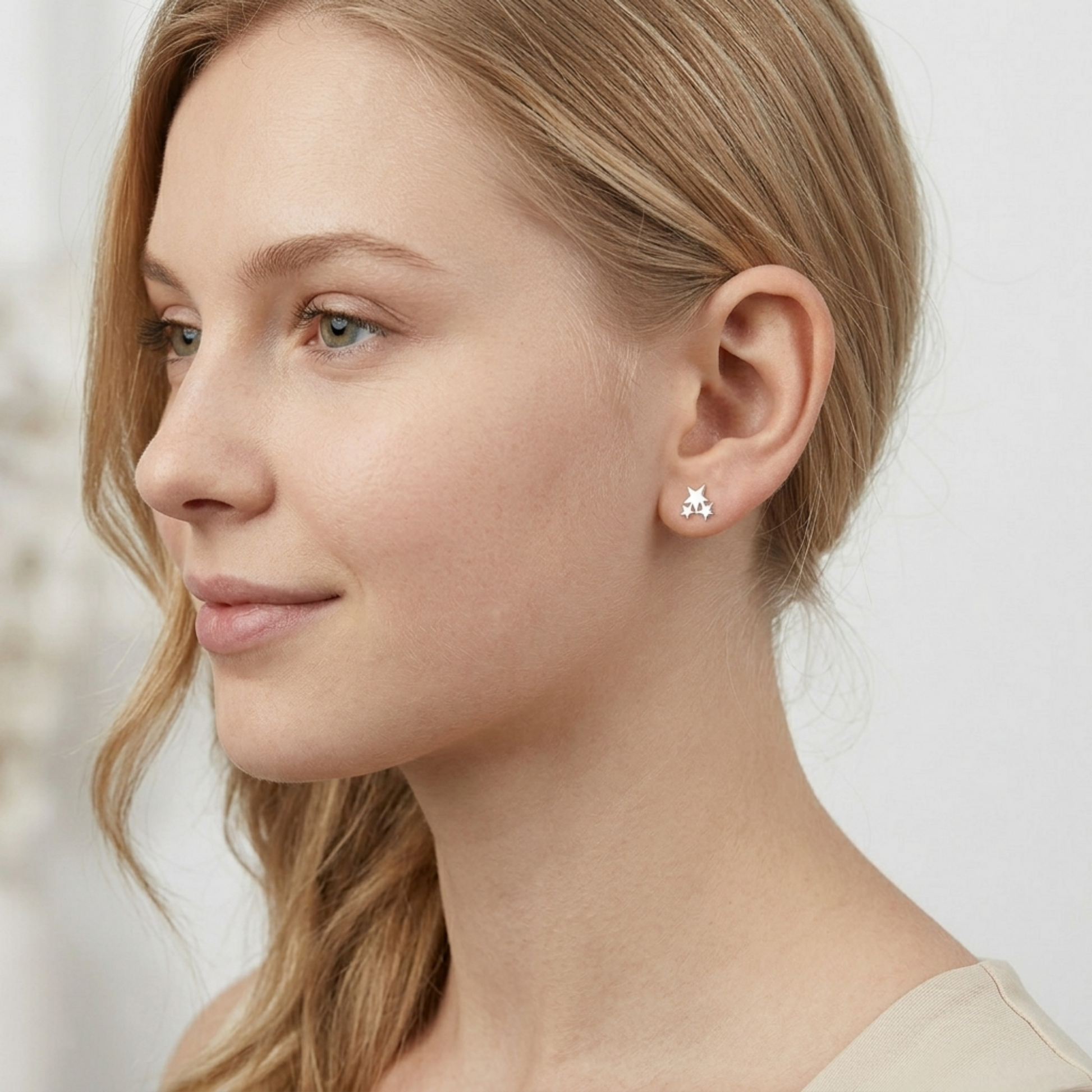 Star stud earrings on person, triple star design in silver-tone