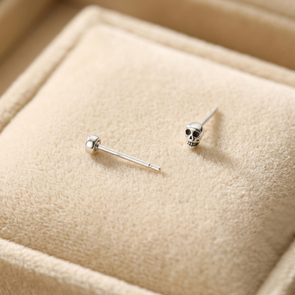 Mini gothic skull stud earrings, one front view with black-eyed skull, silver-tone post