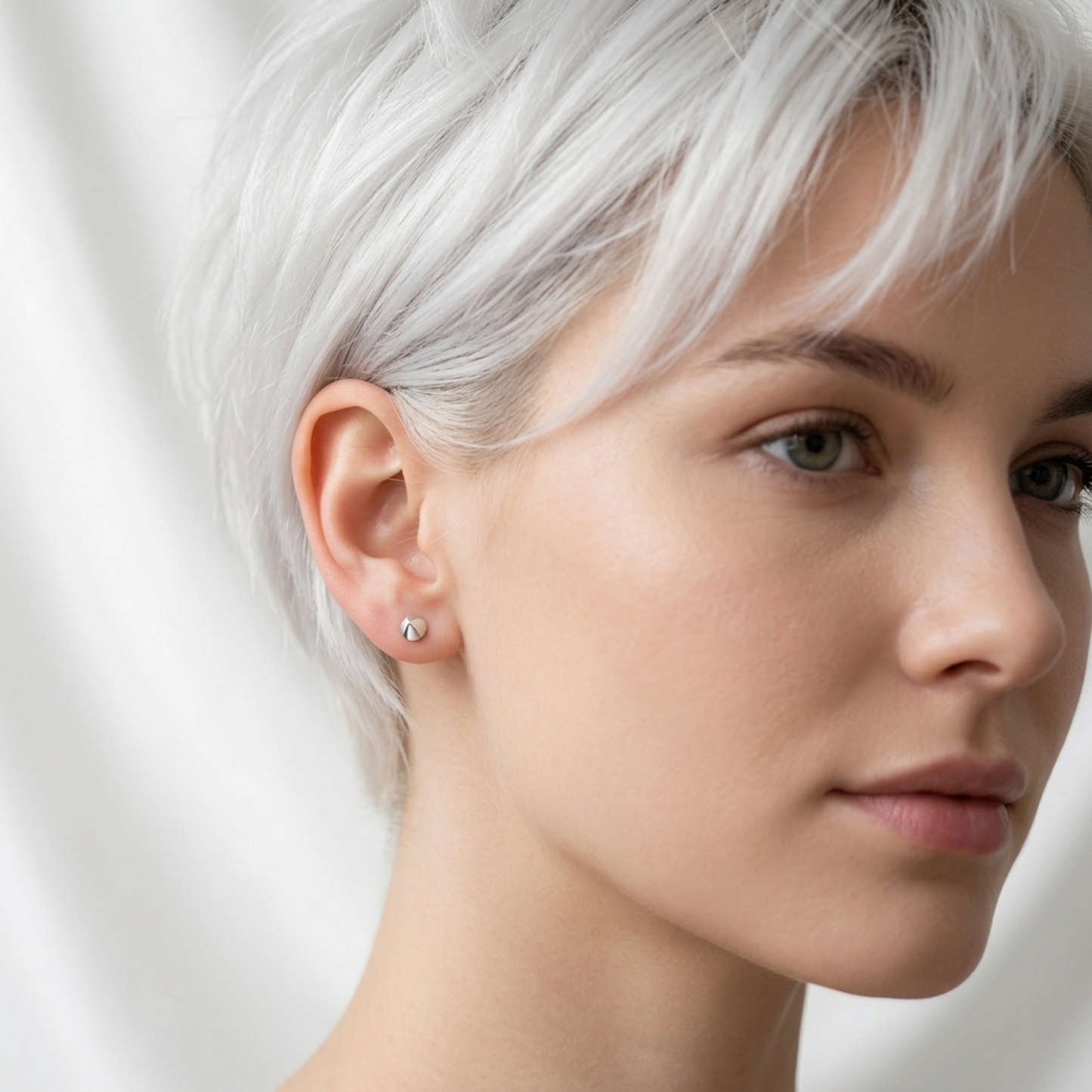 Wearing circular cone spike stud earrings, silver-tone pointed cones on earlobe