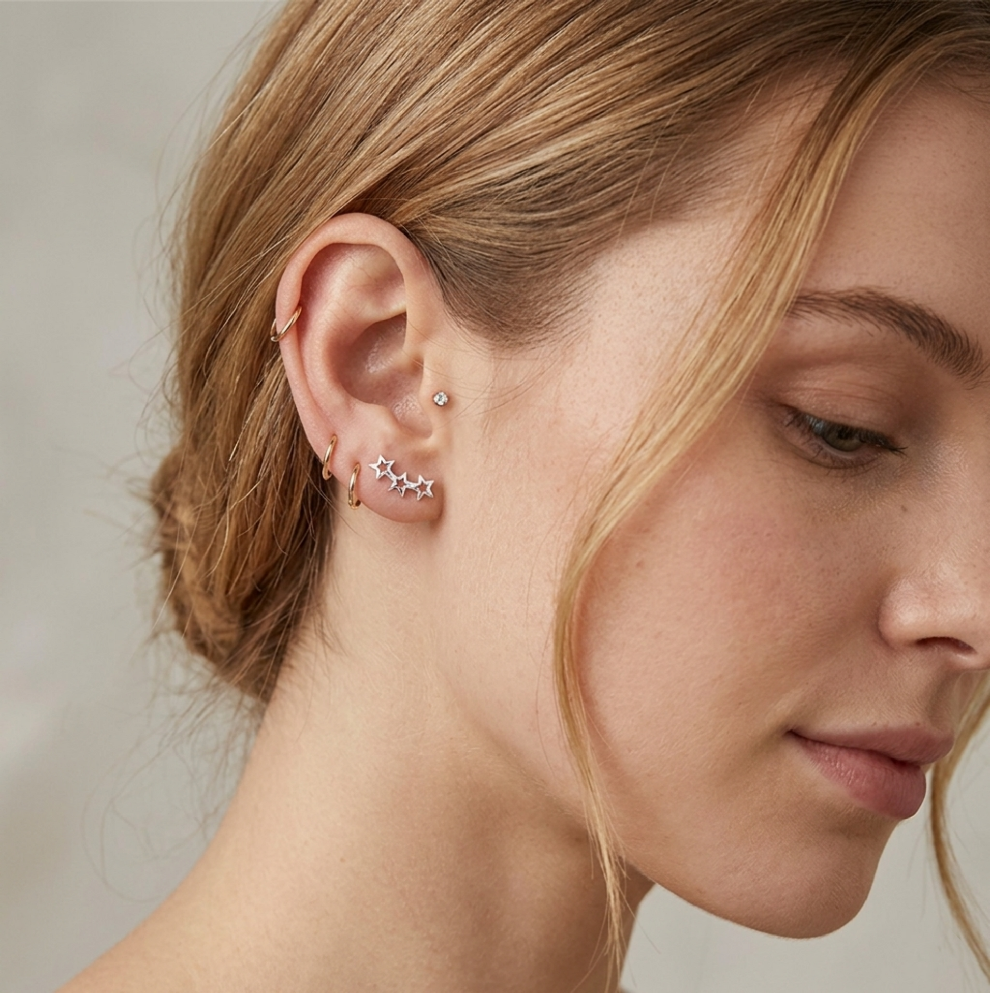 Silver-tone hollow star earrings worn on ear: linked constellation of stars