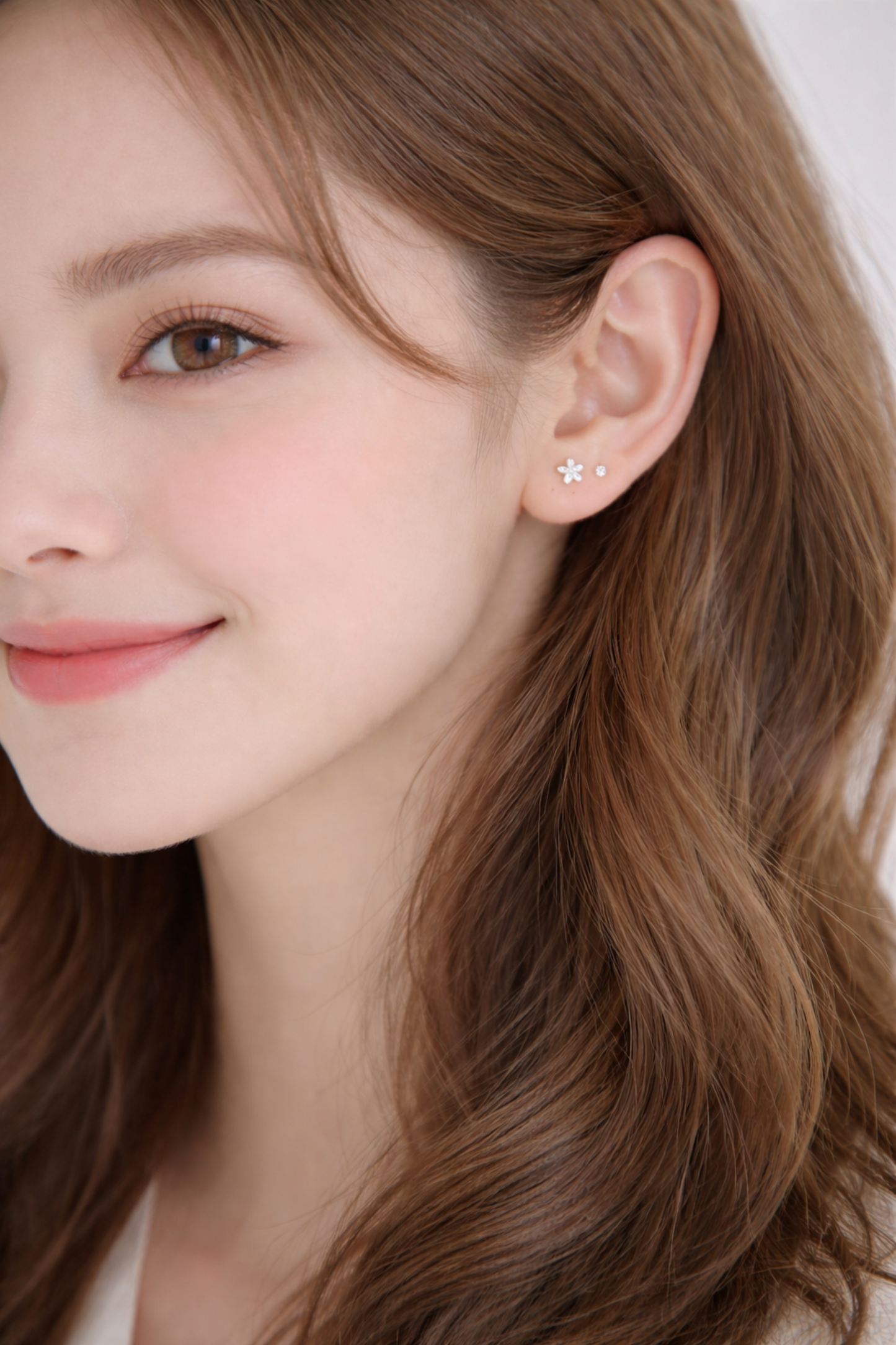 Lily flower stud earrings on ear of model, close-up