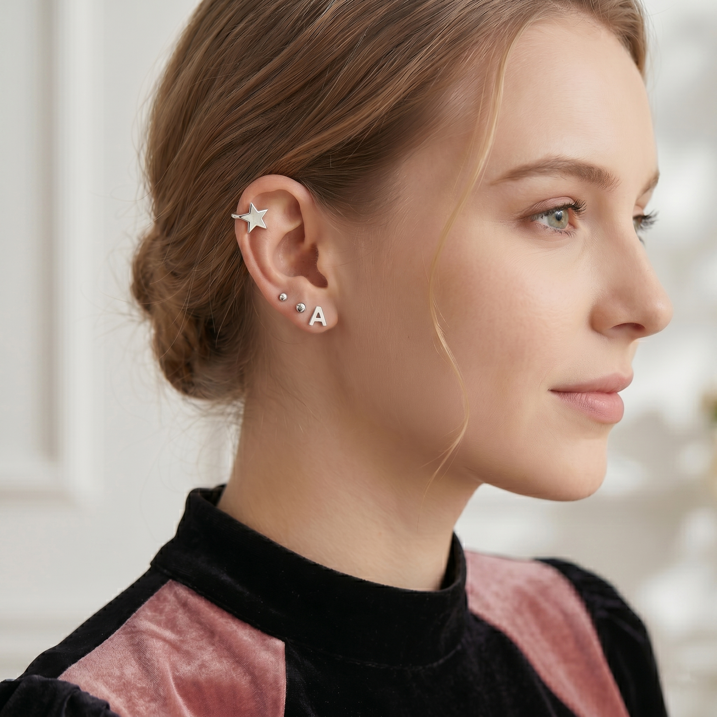 A initial stud earrings, silver-tone studs on the ear