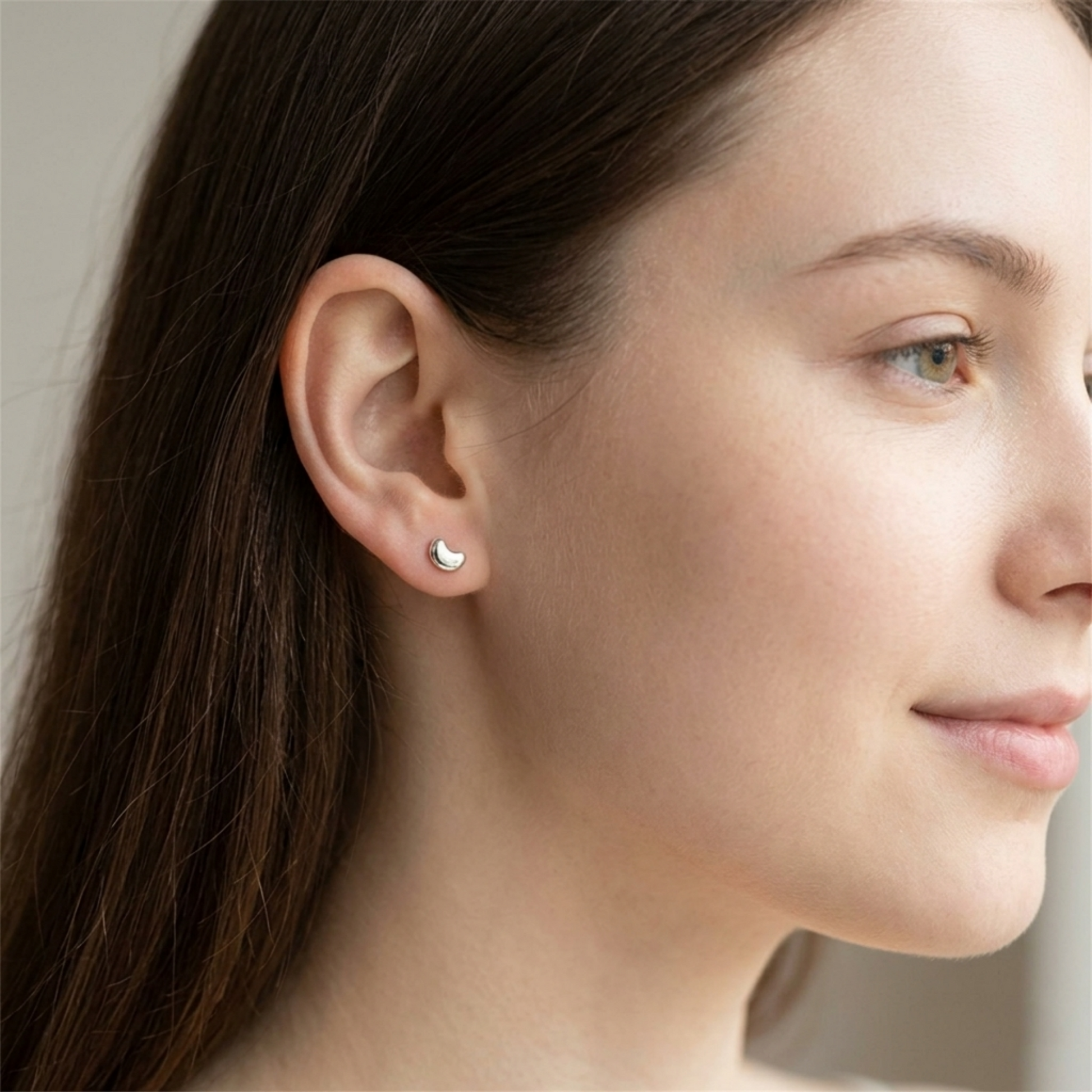 Puffy Moon Studs am Ohr: kleine, silberfarbene Mondsymbole