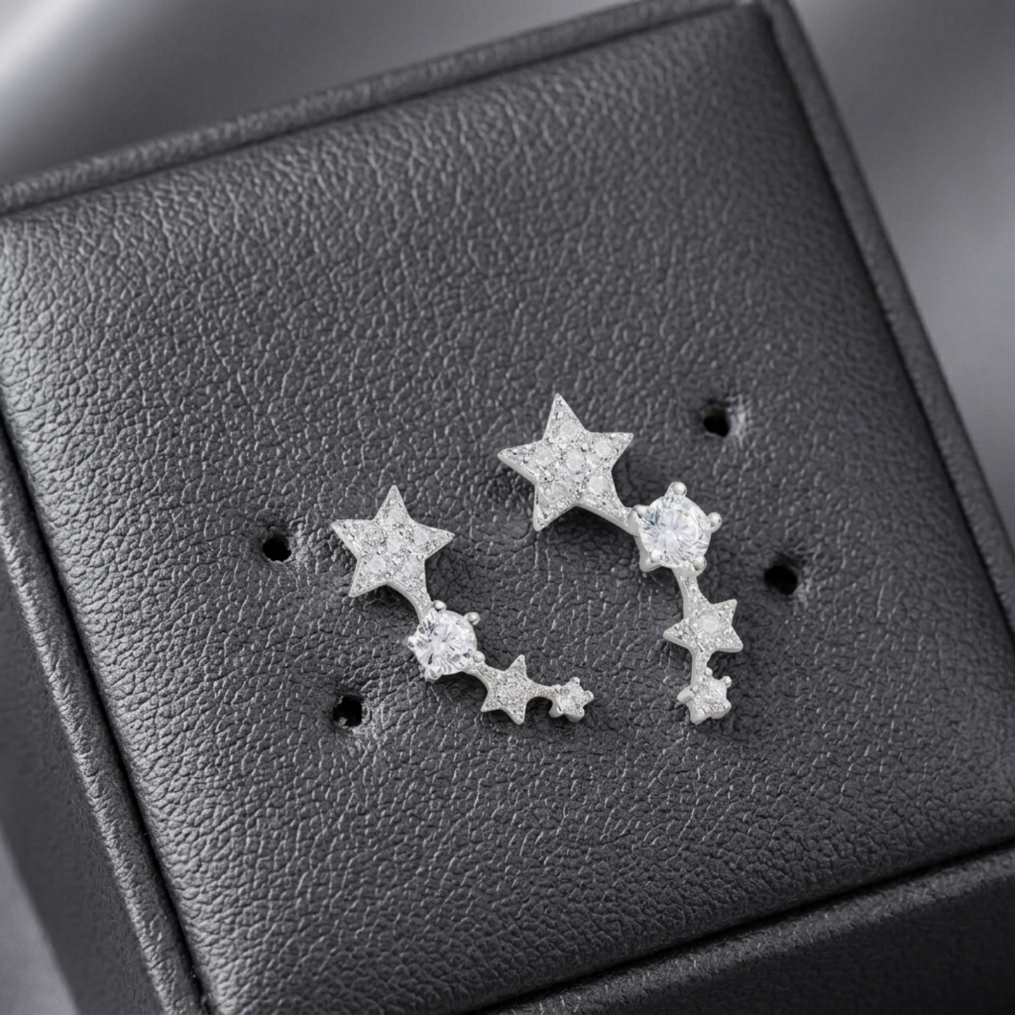 Close-up of linked star CZ ear climbers: two stars and stones on silver-tone metal