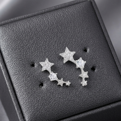 Close-up of linked star CZ ear climbers: two stars and stones on silver-tone metal