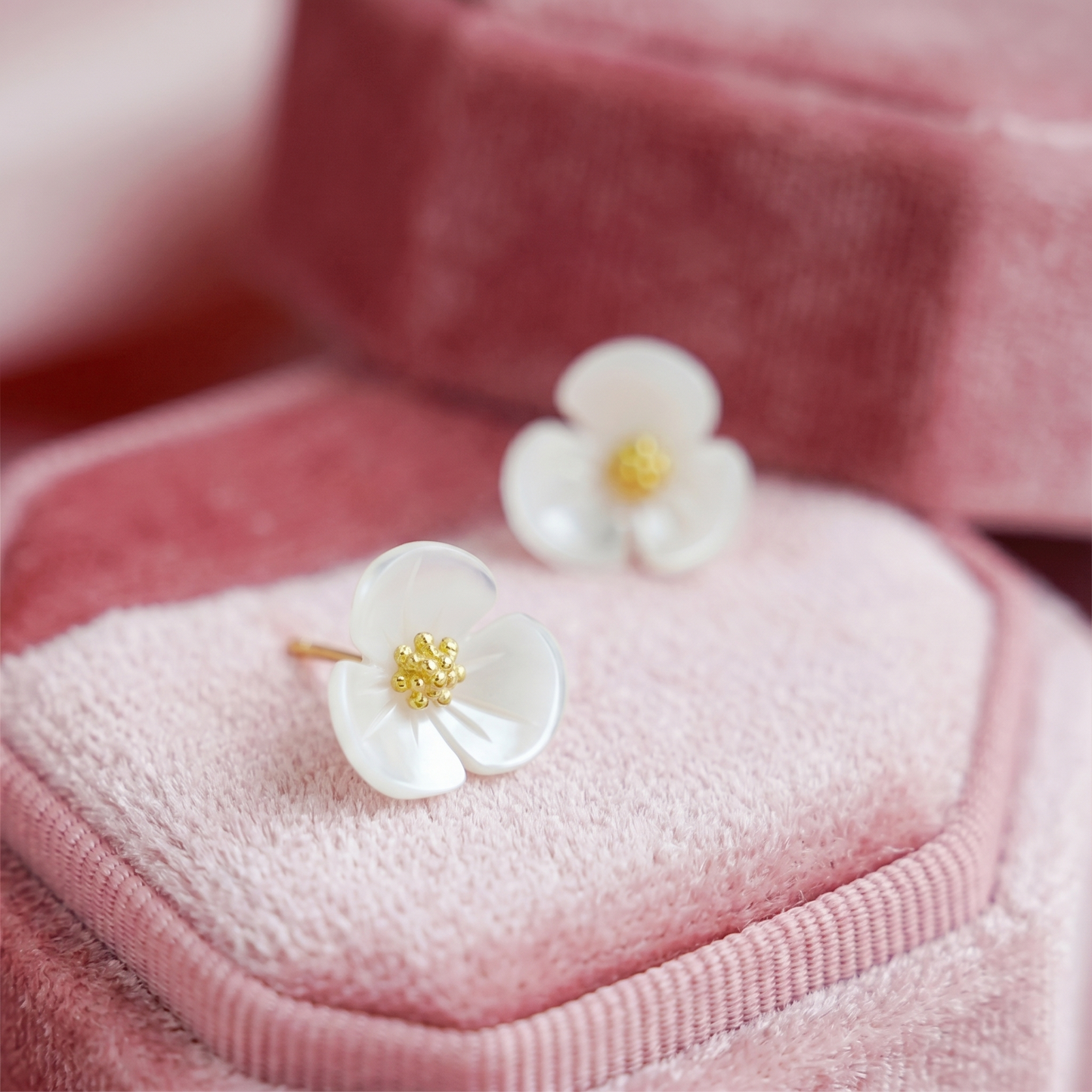 White shamrock stud earrings with gold center florets, close-up front view