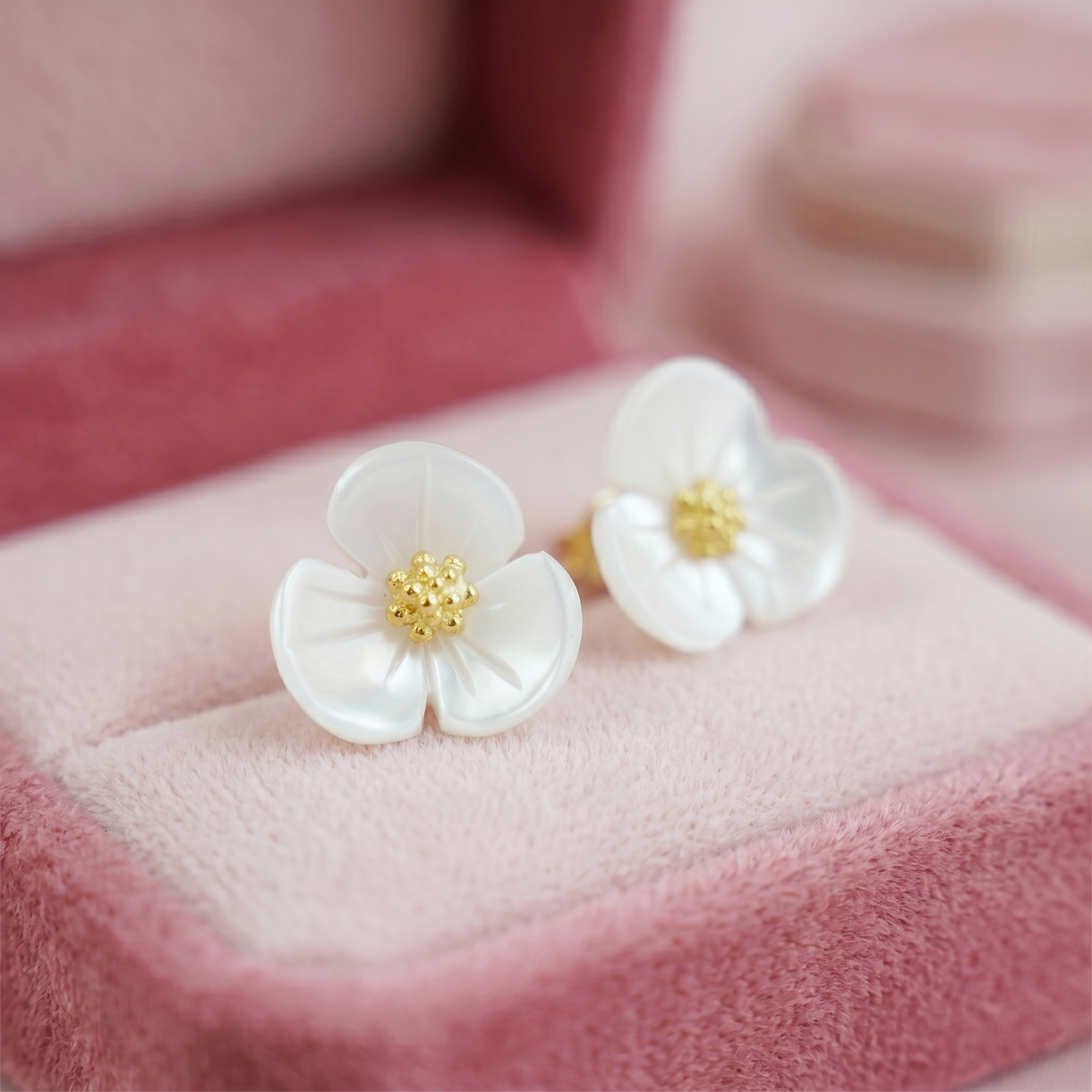 White mother-of-pearl shamrock stud earrings with gold centers, close-up front view