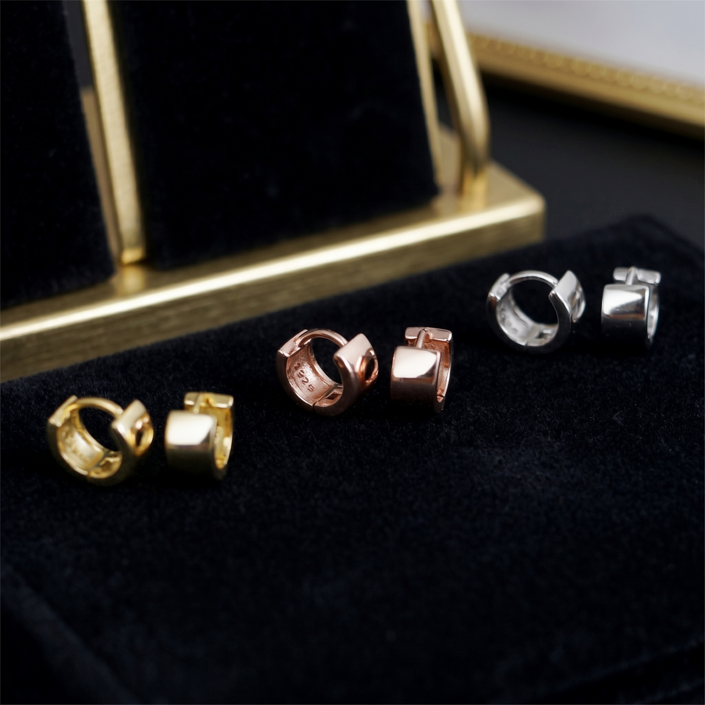 Close-up of huggie hoop bands in Rose Gold, Gold and Rhodium finishes