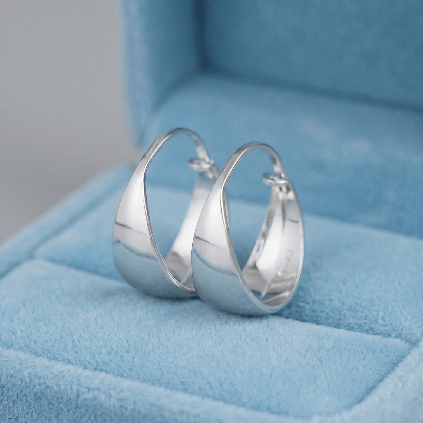 Silver wide dome huggie hoop earrings, angled close-up with smooth domed exterior