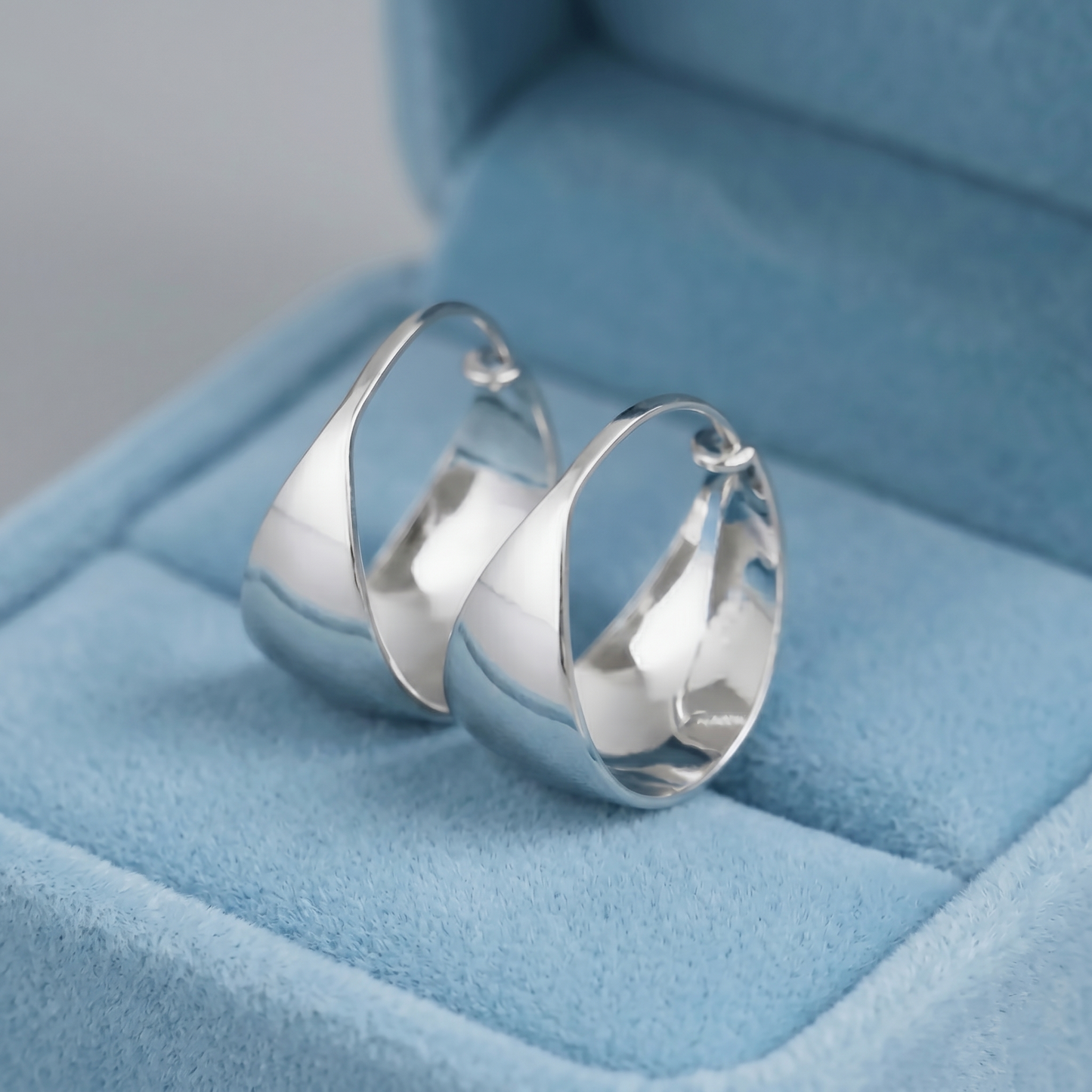 Silver wide dome huggie hoop earrings, front view with reflective inside surfaces