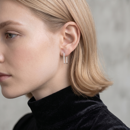 Geometric rectangle huggie earrings in silver tone on a model