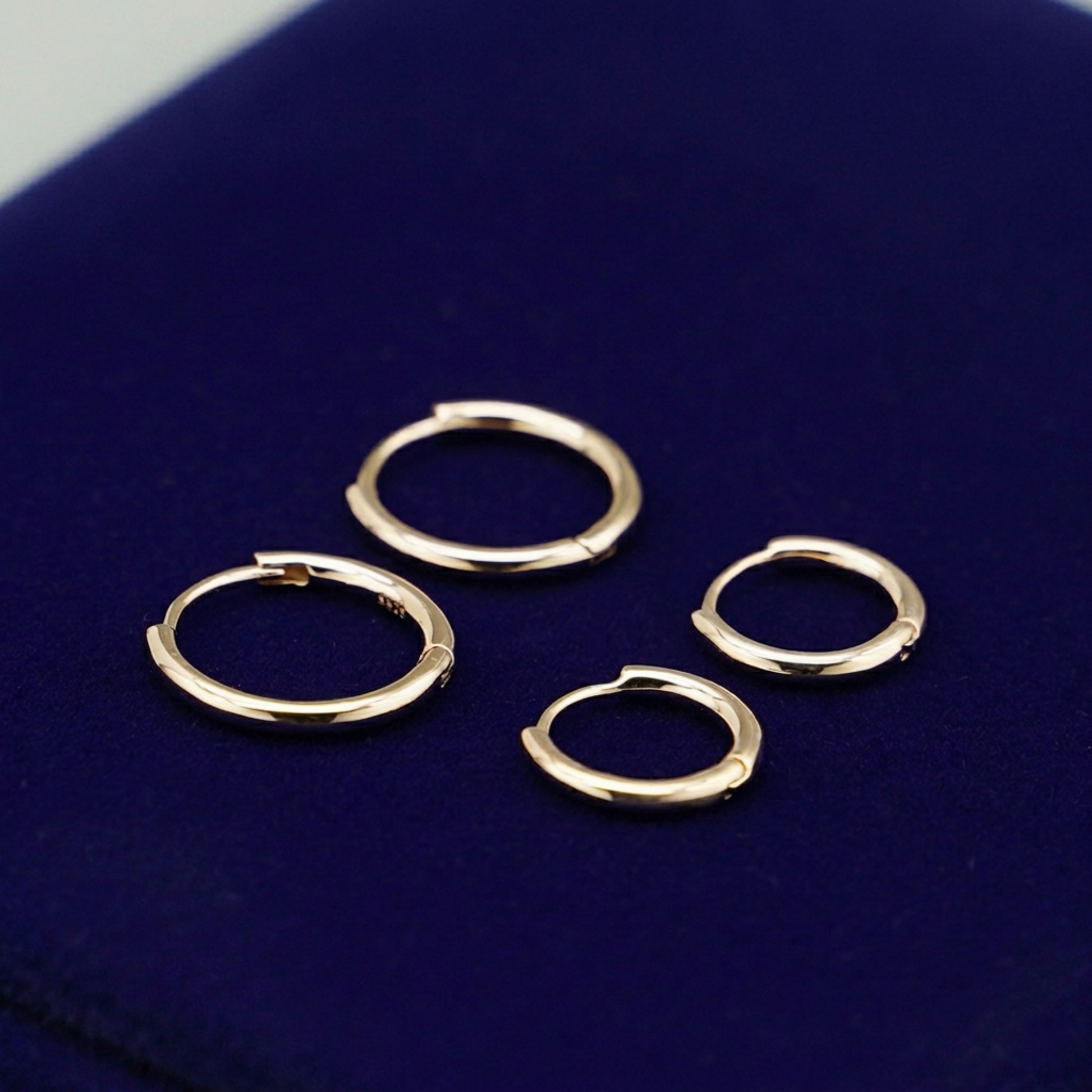 Rhodium 2mm sleeper huggies, multiple small hinge hoops on display